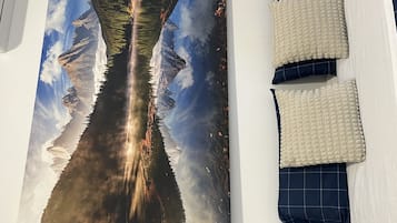 A wall with a large landscape photograph and two pillows.