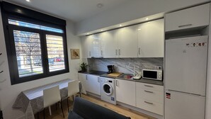 Een kleine keuken met een wasmachine, magnetron en een koelkast.