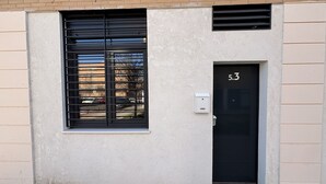 Fachada de un edificio con una puerta negra marcada con el número "5.3", una ventana con persianas horizontales y un buzón pequeño.