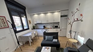 Un espacio habitable compacto con kitchenette, comedor y zona de estar.