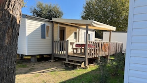 A mobile home with a porch, a deck, and a small garden area. - Mobile Home 'Chez Sylvie' with Shared Pool, Wi-Fi, and Air Conditioning (Argelès-sur-Mer)