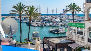 A marina with numerous boats docked, a restaurant named "The Quays Irish Bar," and a satellite dish on a building. - Chanquete 2310  One Bedroom (Manilva)