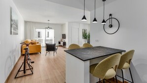 A modern kitchen with a marble countertop, a dining area with chairs, and pendant lights. - Chanquete 2310  One Bedroom (Manilva)