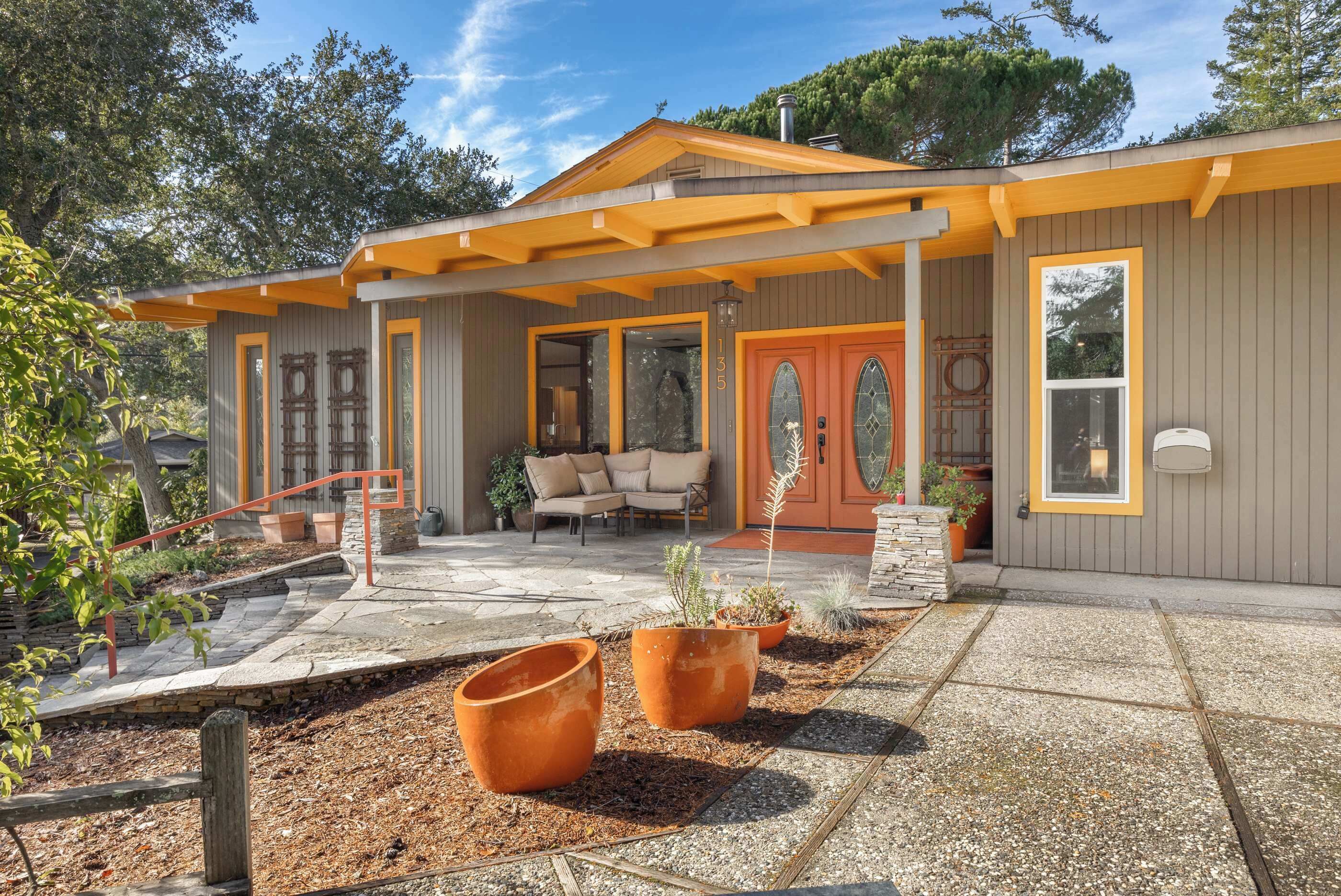 A house with a covered porch, a stone patio, and a number '135' on the door.
