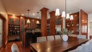 A spacious kitchen with wooden cabinets, a dining table with chairs, and pendant lighting. - HOT TUB - Ping-Pong - BBQ Terrace - Free Shuttle (Mont-Tremblant)