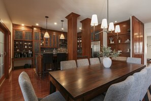 Una cocina moderna con armarios de madera, una mesa de comedor con sillas e iluminación colgante.