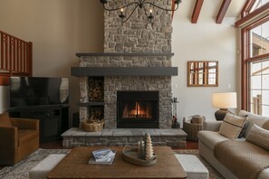 Una sala de estar con chimenea de piedra, un televisor y un sofá.