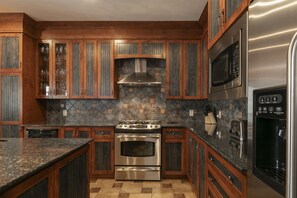 Una cocina con armarios de madera, estufa de acero inoxidable y microondas.