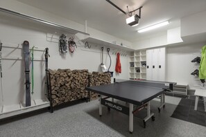 Una habitación con mesa de ping pong, esquíes y un proyector en el techo.
