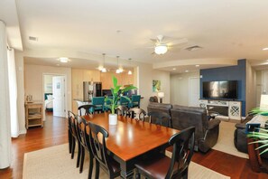 A spacious living area with a dining table, chairs, a sofa, and a TV.