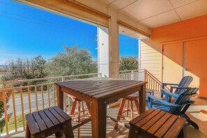 Ein Balkon mit Holztisch und -stühlen, Blick auf die Straße, und ein Gebäude im Hintergrund.