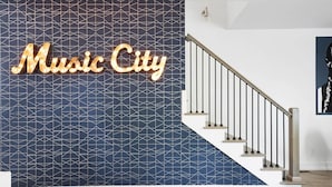 A staircase with a geometric patterned wall and a sign that reads "Music City".