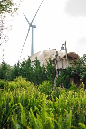 A wind turbine and a building with a dome-like structure surrounded by dense greenery. - Cloud9 & Cloud View Glamping (Xuan Truong - Da Lat)