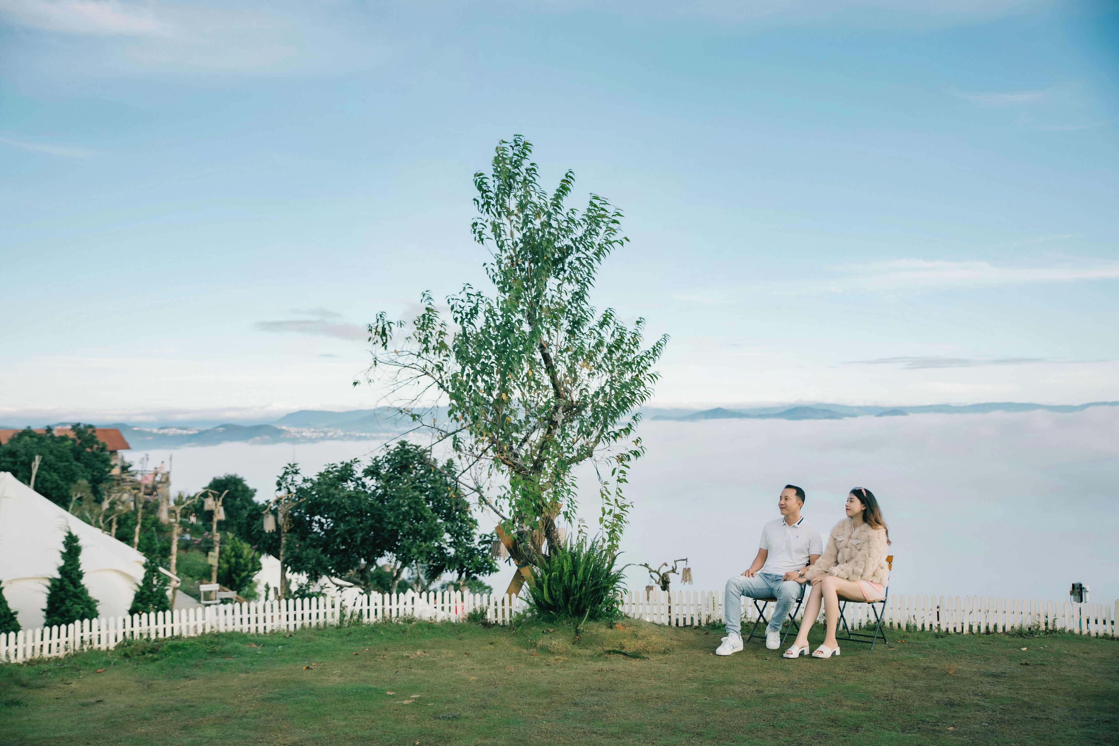 A couple sitting on a bench with a view of a lake and mountains in the background.