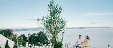 A couple sitting on a bench with a view of a lake and mountains in the background.