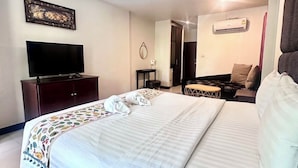 A modern hotel room with a large bed, a flat-screen TV, a wardrobe, and a small table. - The leaf&pool hostel (Koh Lan)