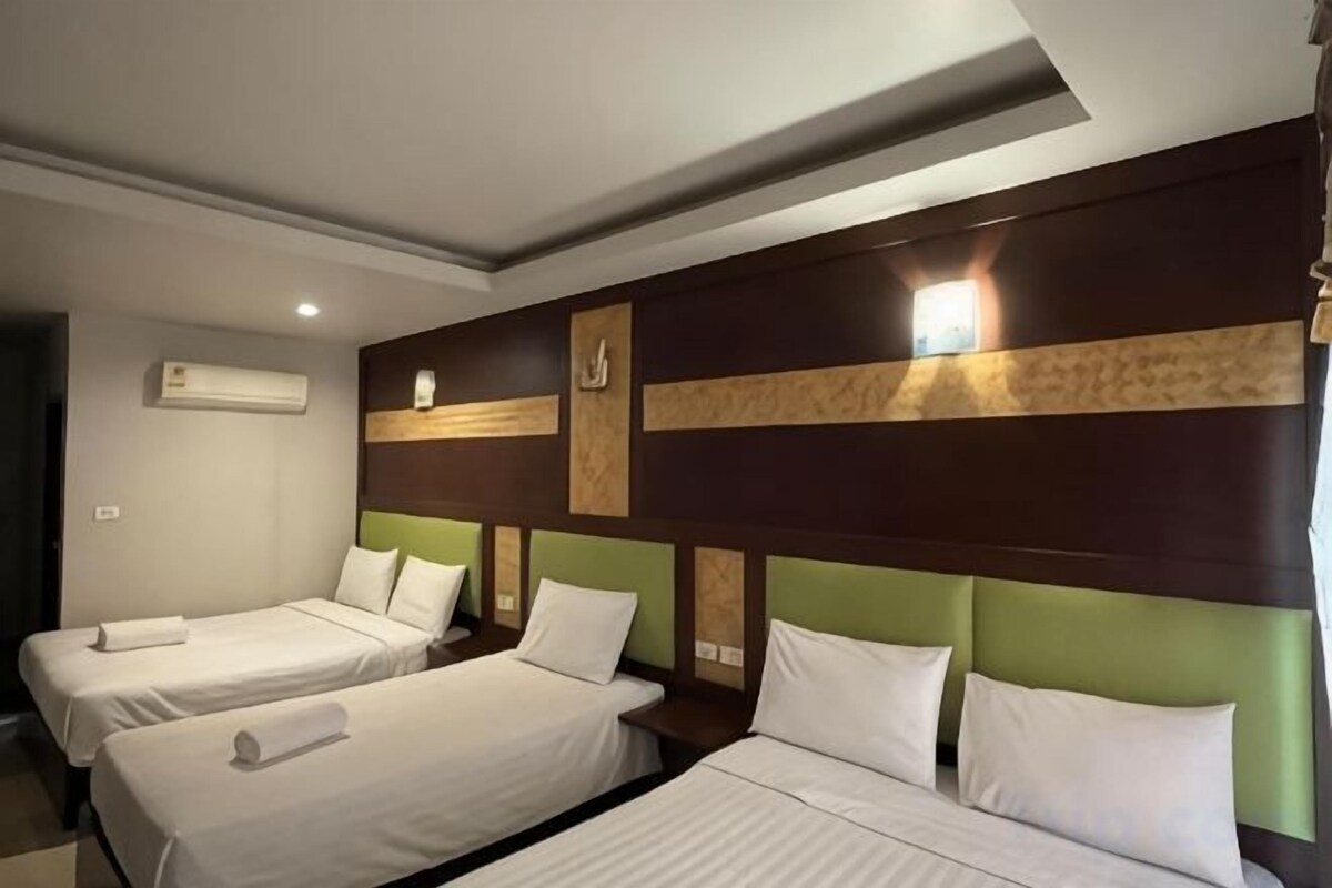 A hotel room with two single beds, a large mirror, and a wall-mounted light fixture.