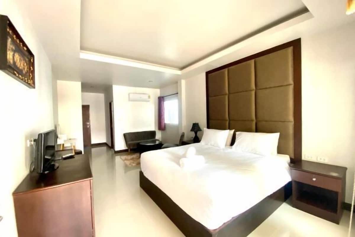 A modern hotel room with a large bed, a desk, a chair, and a television.