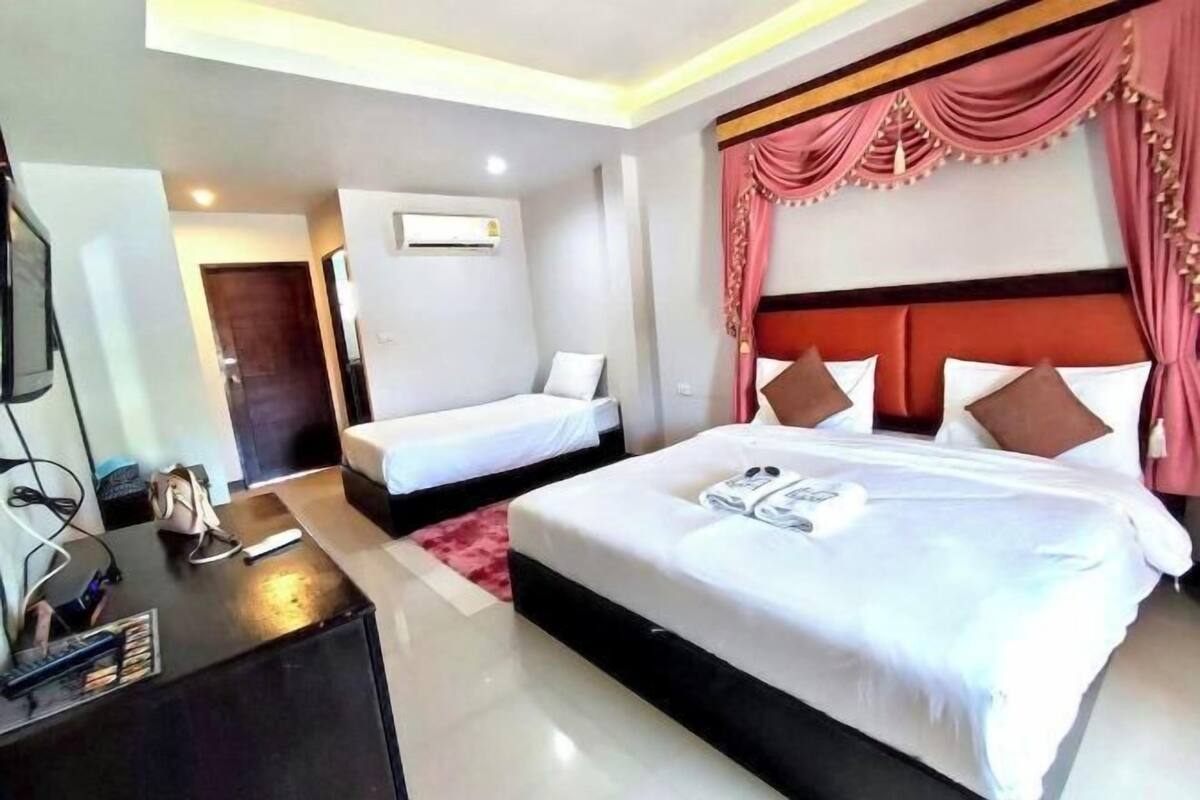 A hotel room with a large bed, a smaller bed, a desk with a computer, and a TV.