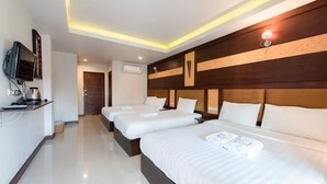 A hotel room with three beds, a TV, a coffee machine, and a flat-screen TV mounted on the wall. - The leaf&pool hostel (Koh Lan)