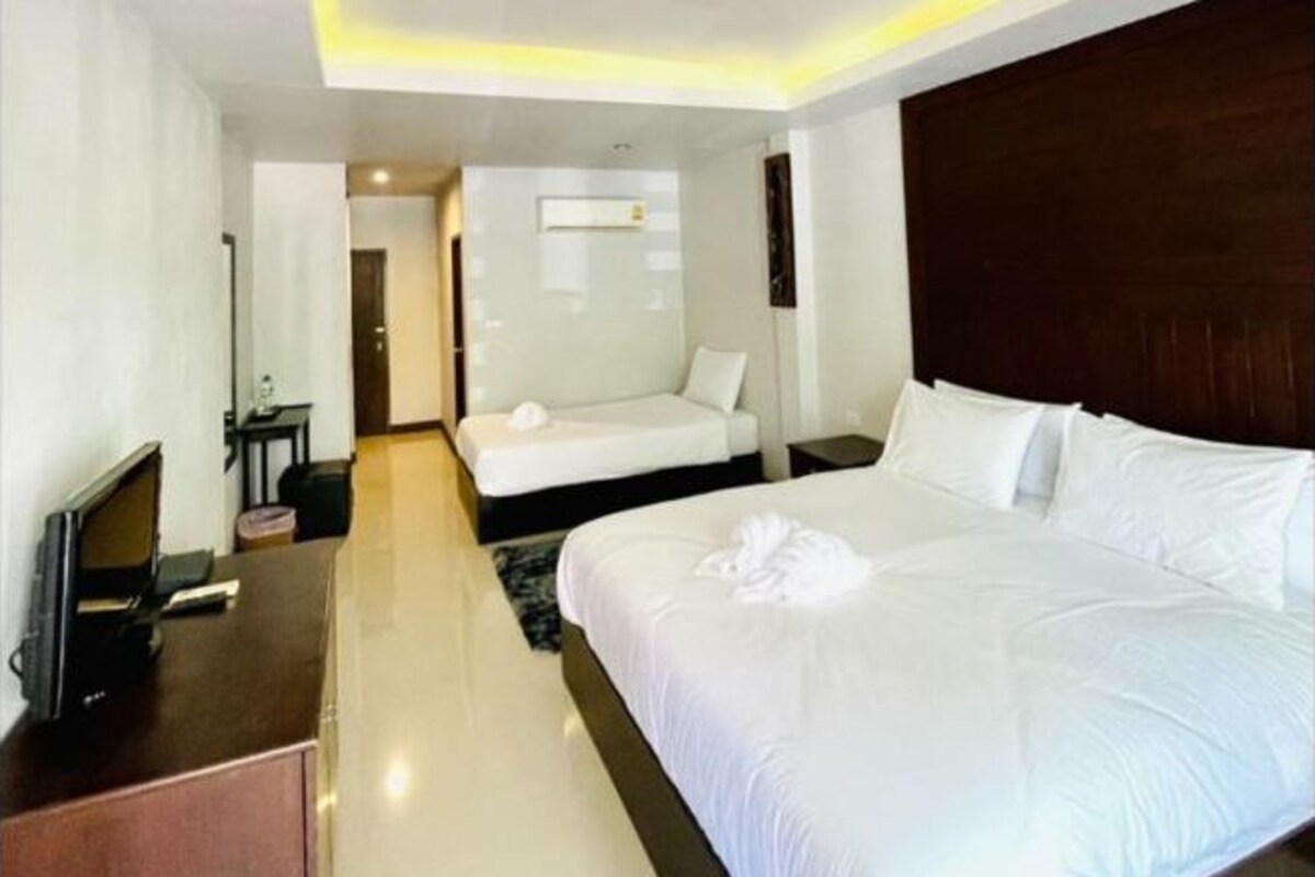 A hotel room with a large bed, a desk with a computer, and a separate seating area with a chair and table.