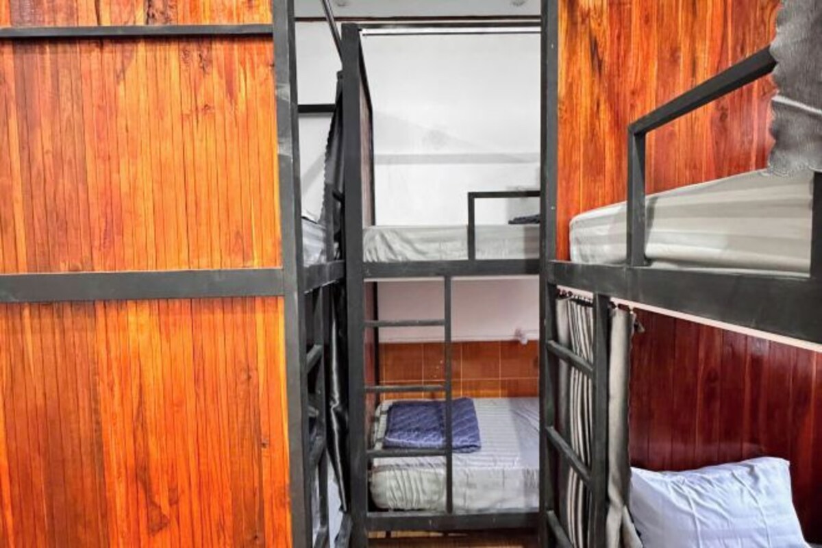 A bunk bed room with wooden walls and a metal frame.