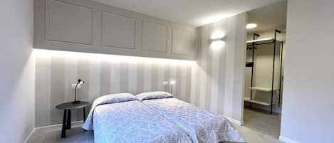 A modern bedroom with a bed, bedside tables, and a walk-in closet.