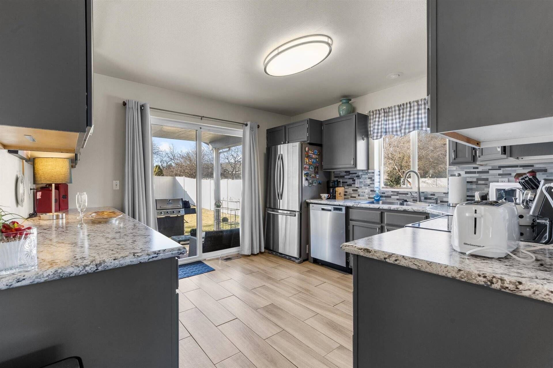 A modern kitchen with a large island, built-in appliances, and a sliding glass door leading to a patio.