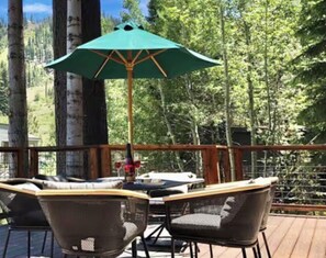 Una terraza de madera con una mesa y sillas, rodeada de árboles.