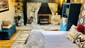 A cozy room with a stone fireplace, a bed with patterned bedding, and a blue cabinet. - ★★Ski In-Out! Mid-Mountain PALISADES home! Hot tub! Views! Walk to village! ★★ (Olympic Valley)