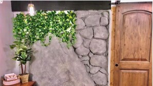 A room with a faux stone wall, a wooden door, and a small table with a basket and a pink item. - ★★Ski In-Out! Mid-Mountain PALISADES home! Hot tub! Views! Walk to village! ★★ (Olympic Valley)
