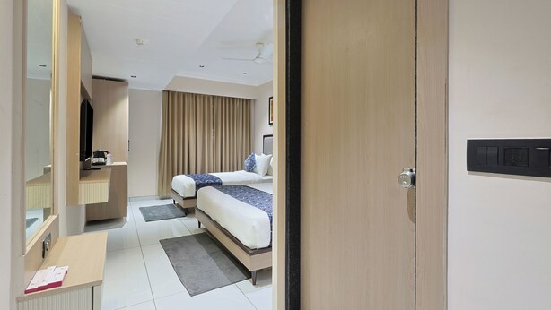 Ein Hotelzimmer mit zwei Betten, einem Schreibtisch, einem Spiegel, einem Kleiderschrank und einem Deckenventilator.