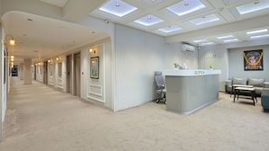 Ein Hotel-Empfangsbereich mit Empfangstresen, Sitzgelegenheiten und einem Korridor mit Türen.