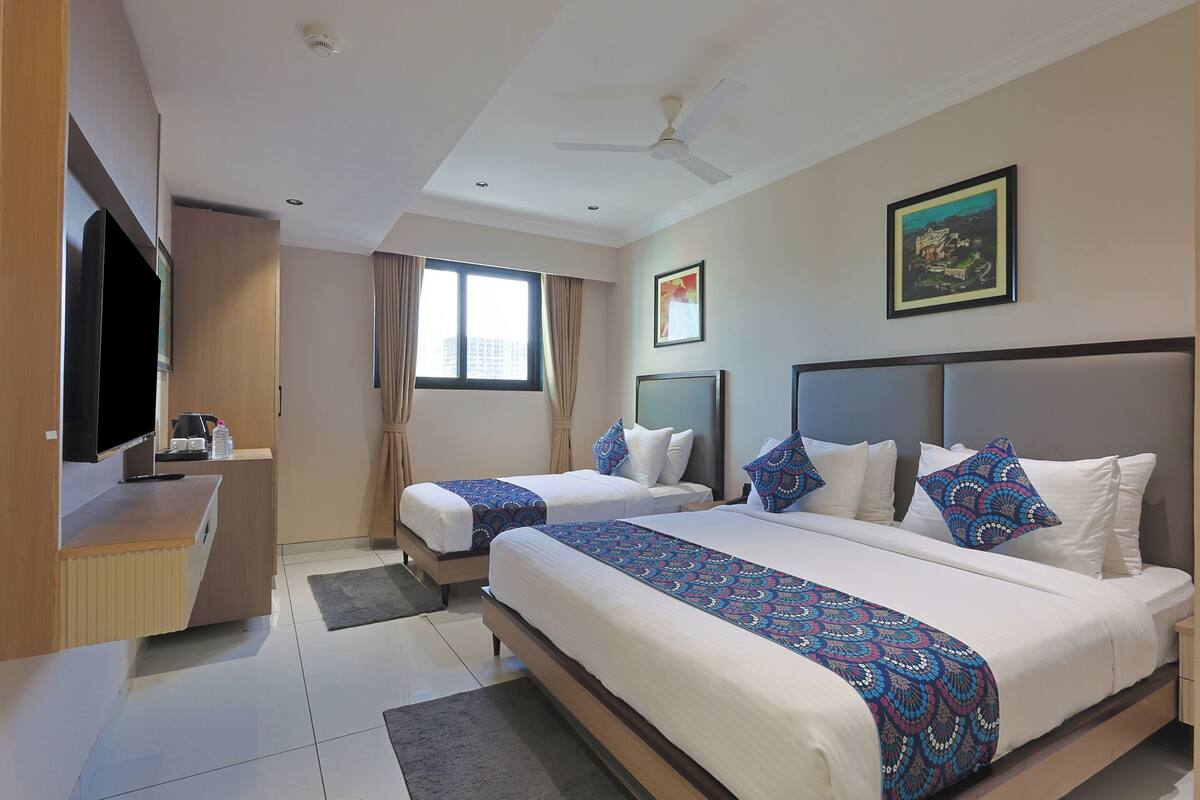 Habitación de hotel con dos camas, un escritorio, televisor y ventilador de techo.