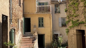 Una calle estrecha con edificios, una escalera y macetas.