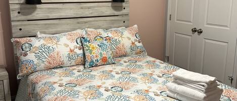 A bedroom with a bed, a nightstand, a wall-mounted lamp, and a door.