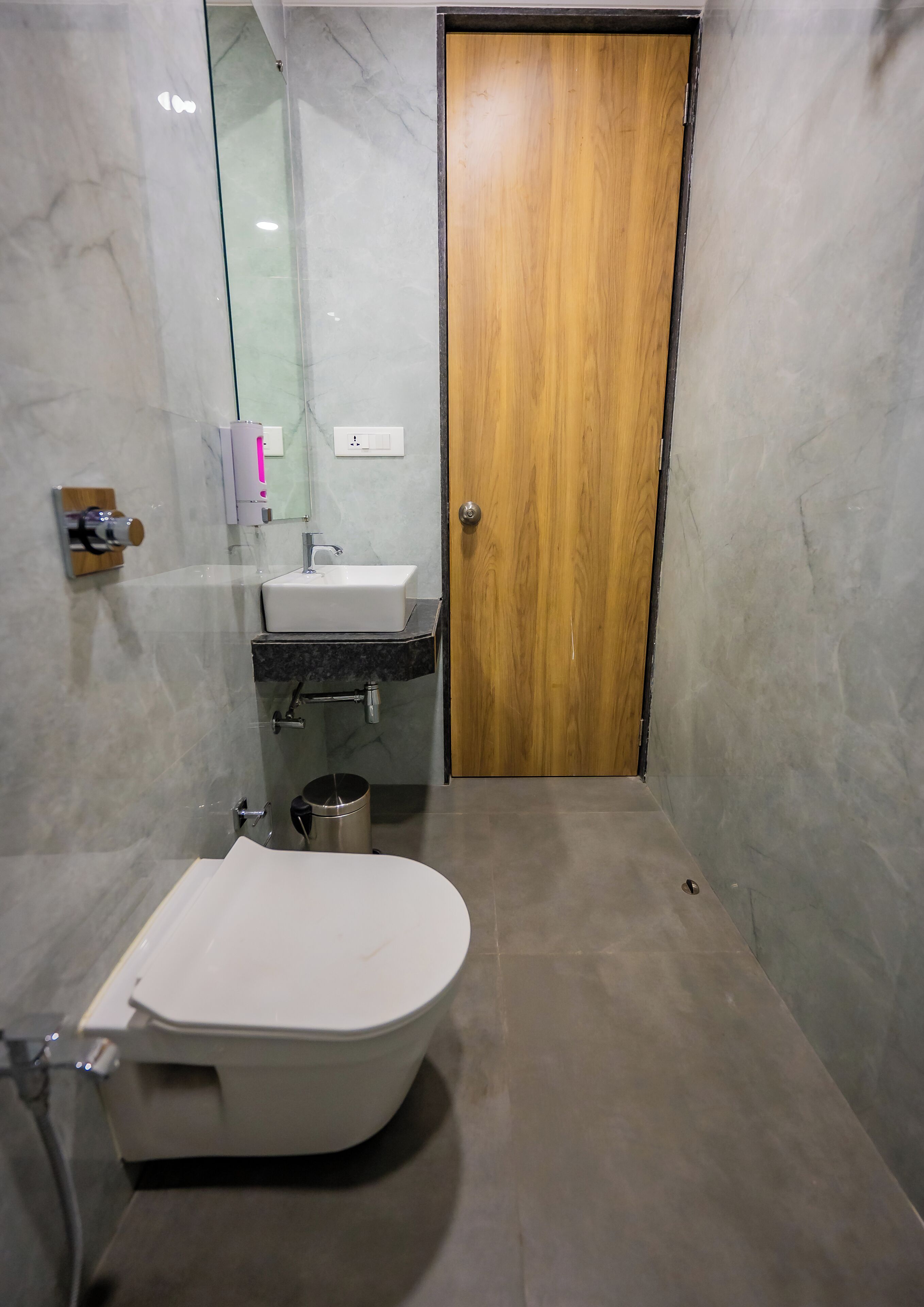 Un baño moderno con una bañera independiente, un tocador con lavamanos y una puerta de madera.