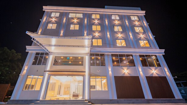 A multi-story hotel with a modern design, featuring a prominent entrance with glass doors and a covered walkway. - Lotus Leaf (Sudhagad)