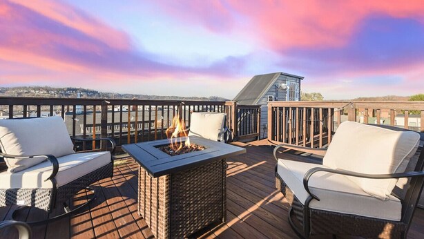 A deck with outdoor seating, a fire pit, and a view of the city skyline.