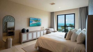 Una habitació d'hotel moderna amb un llit gran, vistes al mar, un quadre a la paret i un moble amb objectes decoratius.