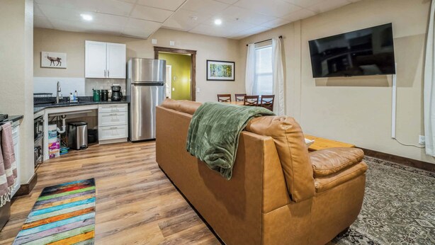 Un espacio habitable compacto con kitchenette, un sofá, un televisor y una alfombra estampada.