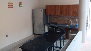 A kitchen with wooden cabinets, a refrigerator, a gas stove, and a black countertop.