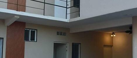 A two-story building with a swimming pool, a balcony, and a dining area.