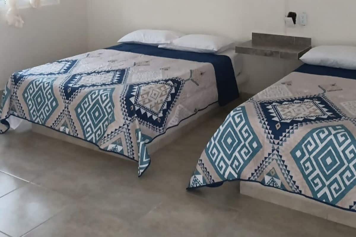 Een kamer met twee bedden, een plafondventilator en een airconditioning.