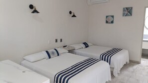 Een hotelkamer met twee bedden, een kleintje tafeltje en een nachtkastje. Er zijn wandlampen en decoratieve objecten aan de muur.