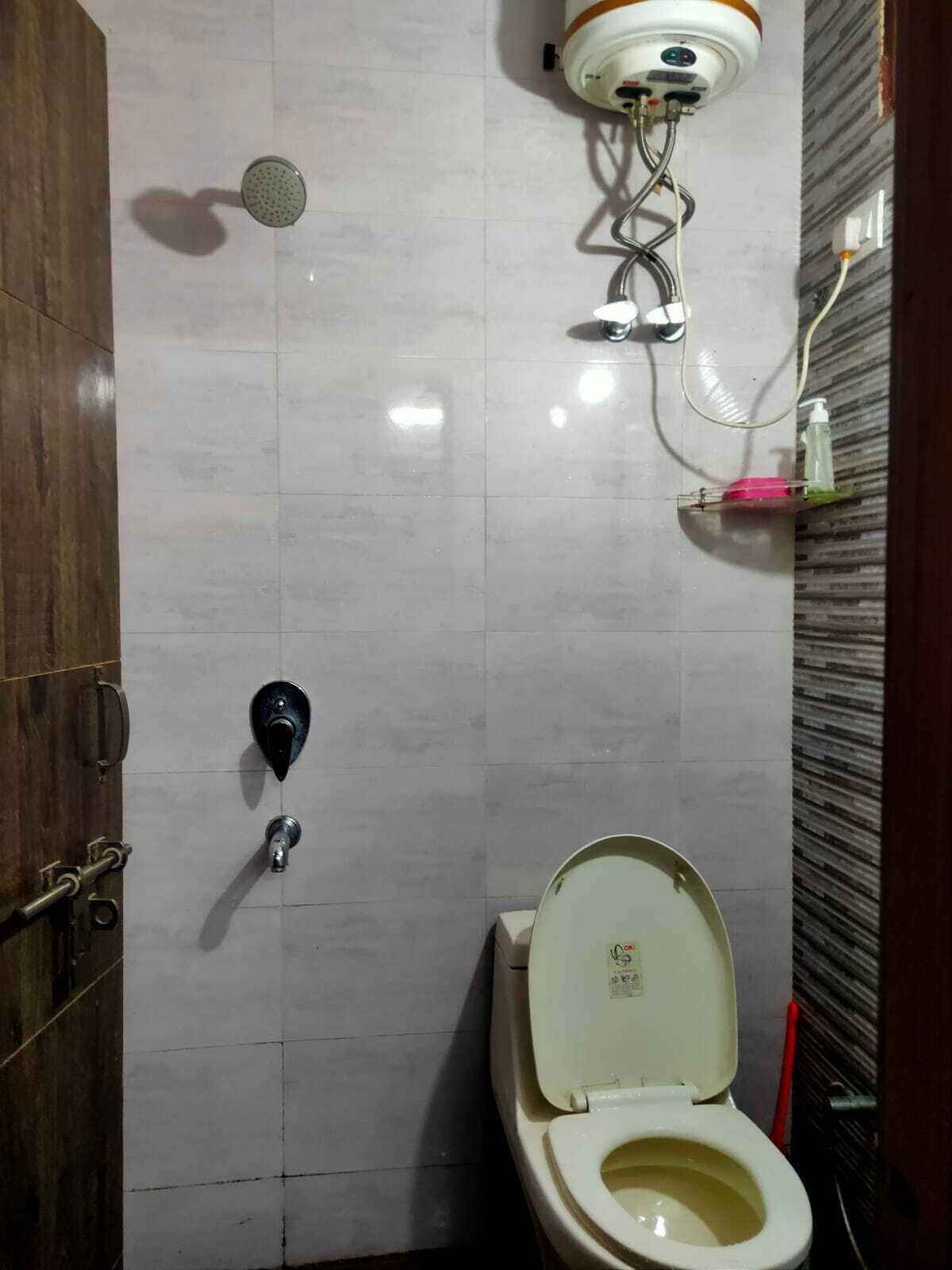 A bathroom with a toilet, a shower, and a hand dryer.