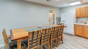 Ein Essbereich mit Holztisch und -stühlen, eine Küche mit Holzausstattung und ein Kühlschrank.