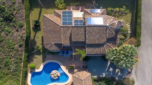 Une grande maison avec une piscine, des panneaux solaires et un jardin.