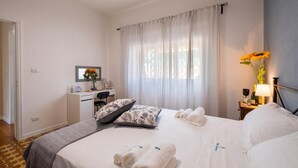 Une chambre d’hôtel avec un lit, un bureau, une chaise, une table de chevet et une fenêtre avec des rideaux.