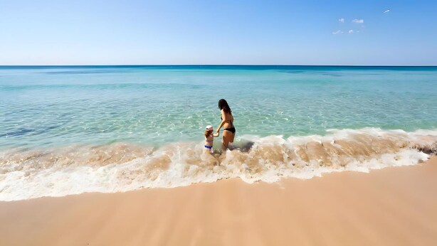 Une scène de plage avec une eau turquoise cristalline et un rivage sablonneux.